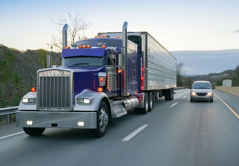 A semi truck passing a car on the highway